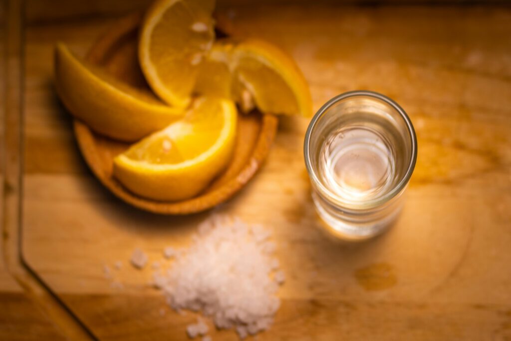 Top view of tequila with sliced lemon and salt on a wooden surface.
